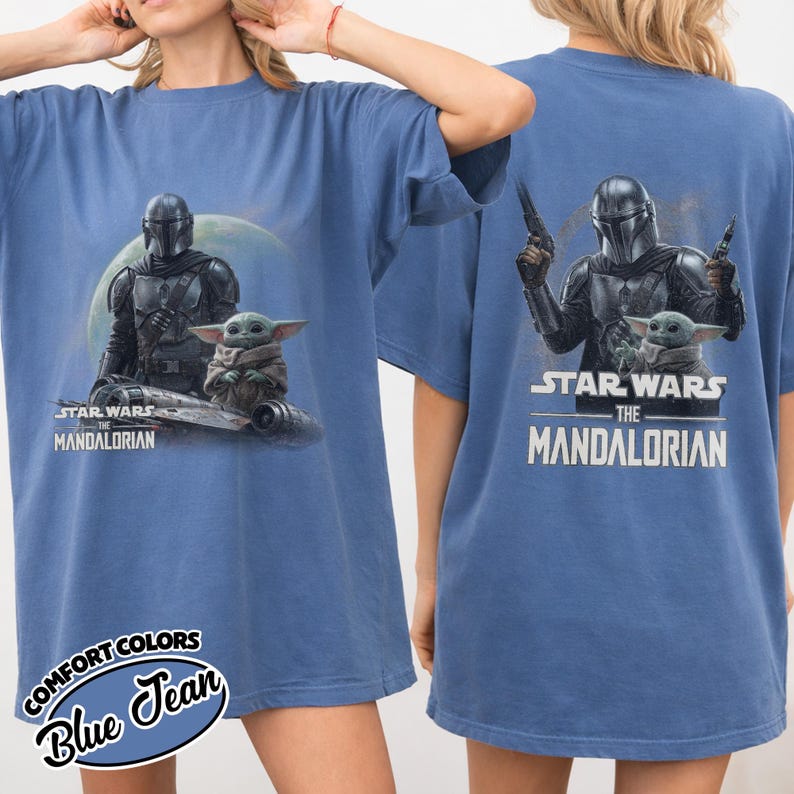 May include: Blue t-shirt featuring a graphic of The Mandalorian and Grogu from Star Wars. The front design shows the characters with the text "Star Wars The Mandalorian". The back of the shirt also has the same graphic and text. The shirt is a Comfort Colors brand.