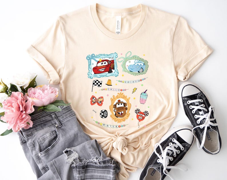 Puede incluir: Camiseta beige con gr&aacute;ficos de coches de dibujos animados coloridos. El dise&ntilde;o incluye im&aacute;genes enmarcadas de coches, una bandera a cuadros y un globo. La camiseta se combina con vaqueros grises y zapatillas negras.