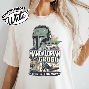 Puede incluir: Camiseta blanca Comfort Colors con un dise&ntilde;o de Star Wars. El gr&aacute;fico incluye el casco mandaloriano, Grogu y el texto "The Mandalorian and Grogu" con la frase "This is the Way."