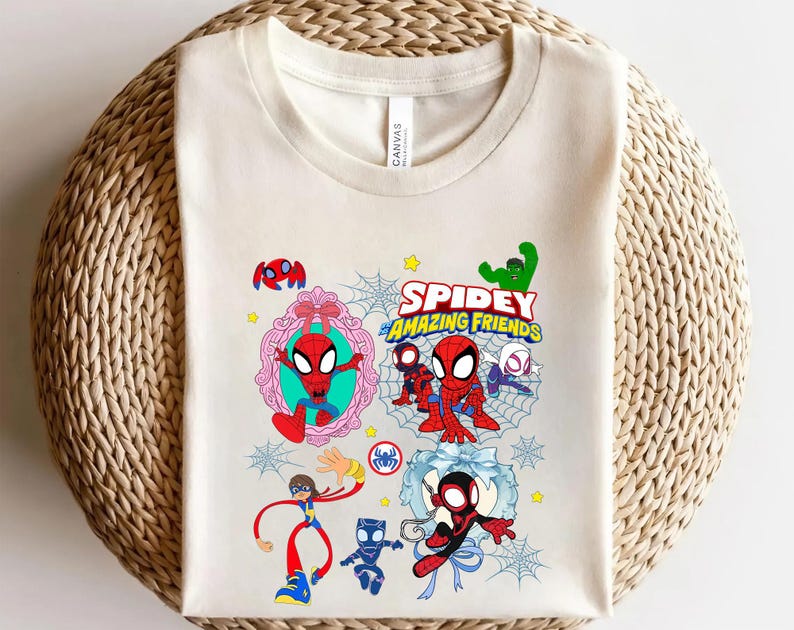 May include: Cream-colored t-shirt featuring a colorful graphic of Spider-Man and friends. The design includes the text "Spidey and His Amazing Friends" with cartoon illustrations of the characters, spider webs, and stars.