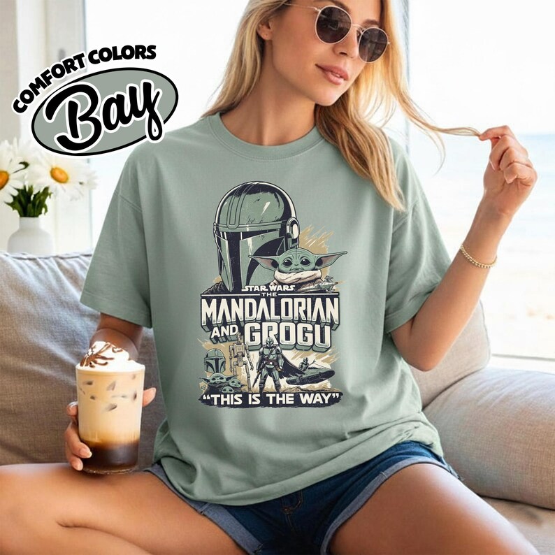 Puede incluir: Camiseta verde salvia con un dise&ntilde;o de Star Wars con The Mandalorian y Grogu. El gr&aacute;fico incluye el casco del Mandaloriano, Grogu y la frase "THIS IS THE WAY". La camiseta tambi&eacute;n tiene el logo Comfort Colors Bay.