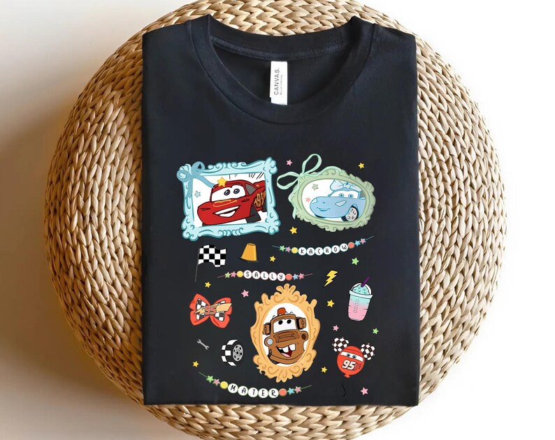 Puede incluir: Camiseta negra con gr&aacute;ficos de coches de dibujos animados coloridos. El dise&ntilde;o incluye im&aacute;genes enmarcadas de un coche de carreras rojo, un coche azul y un cami&oacute;n marr&oacute;n. Elementos adicionales: bandera a cuadros, rayo y batido.