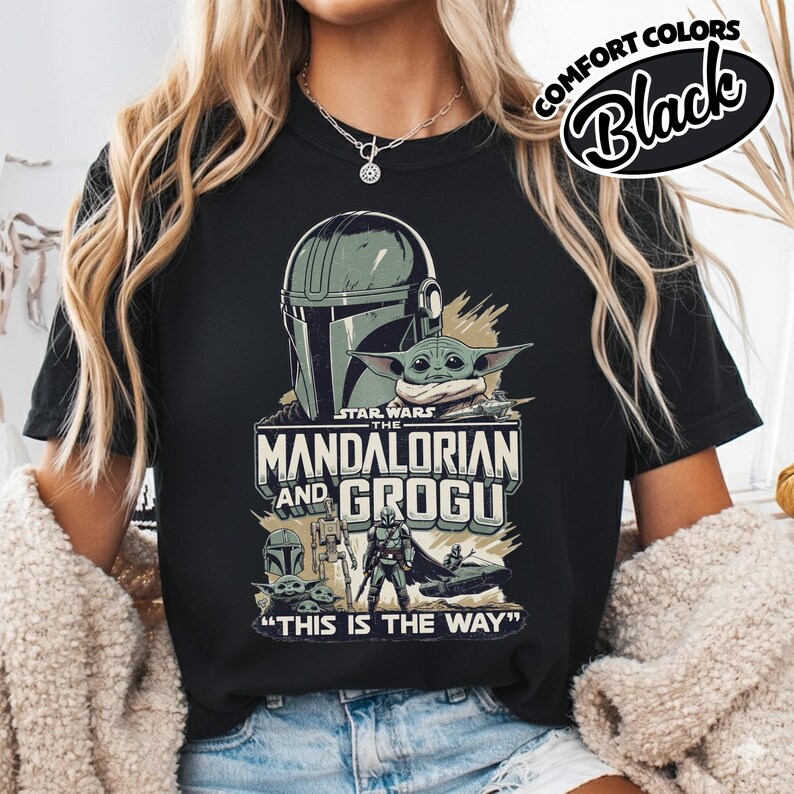 Puede incluir: Camiseta negra con un gr&aacute;fico de Star Wars que presenta a The Mandalorian y Grogu. El dise&ntilde;o incluye el casco del Mandaloriano, Grogu y la frase "THIS IS THE WAY". La camiseta tambi&eacute;n tiene el texto "COMFORT COLORS Black".