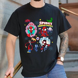 May include: Black t-shirt featuring a colorful graphic of Spider-Man and friends. The design includes the text "Spidey and His Amazing Friends" with various cartoon illustrations of the characters. The shirt is a crew neck style.