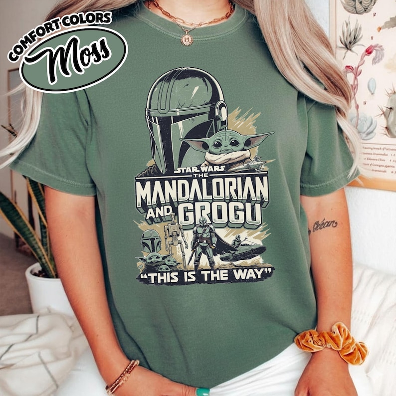 Puede incluir: Camiseta verde con un dise&ntilde;o gr&aacute;fico de la serie Star Wars, "The Mandalorian and Grogu". El dise&ntilde;o incluye el casco mandaloriano, Grogu y la frase "This is the Way". La camiseta tambi&eacute;n tiene el texto "Comfort Colors" y "Moss".