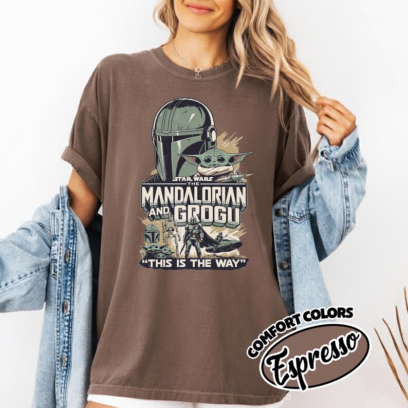 Puede incluir: Camiseta color espresso con un gr&aacute;fico de The Mandalorian y Grogu de Star Wars. El dise&ntilde;o incluye el casco del Mandaloriano, Grogu y el texto "THIS IS THE WAY". La camiseta es parte de la colecci&oacute;n Comfort Colors.