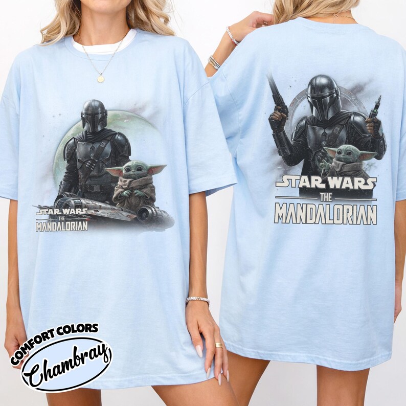 May include: Light blue t-shirt featuring a graphic of The Mandalorian and Grogu from Star Wars. The front shows the characters with a ship, and the back shows them with the text "Star Wars The Mandalorian".