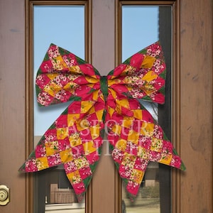 May include: A large decorative bow made of quilted fabric featuring a patchwork pattern of pink floral, solid yellow, and green diamond shapes. The bow is centered on a glass door panel and has the text ASFOUR STITCH overlaid in white letters.