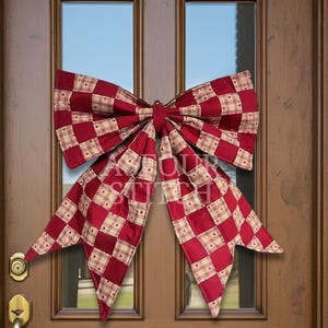 May include: A large decorative bow featuring a checkered pattern of deep red and cream squares with small heart motifs. The fabric bow is mounted on a brown wooden door with glass panels and includes the text "OUR STITCH" overlaid on the center.
