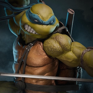 May include: A detailed sculpture of Leonardo, a Teenage Mutant Ninja Turtle, with a fierce expression. He wears a blue mask and has a brown chest and arm straps. A katana blade is visible. The figure has a textured, reptilian appearance.