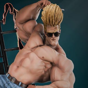 May include: A muscular figurine of a man in blue jeans and sunglasses, with a blonde pompadour hairstyle. The figure is posed with one arm raised, and the word "MOTEL" is displayed in neon lights behind him. A teddy bear and a bouquet of red flowers are at his feet.
