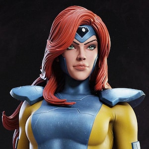 May include: A detailed statue of a female character with red hair and green eyes. She wears a yellow and blue bodysuit with a belt featuring an X symbol. The figure has a determined expression and a blue headpiece.