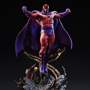 Op de afbeelding: Een gedetailleerd beeldje van Magneto, een stripboekpersonage, in een dynamische pose. Het figuur is gekleed in een rood en paars kostuum met een helm, cape en laarzen. Het beeld is gemonteerd op een rotsachtige, metalen basis, met de armen geheven.