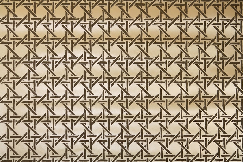 May include: A close-up of a woven pattern with a repeating geometric design. The pattern features dark brown intersecting lines against a light beige background, creating a textured, grid-like appearance. This design is reminiscent of rattan or wicker.