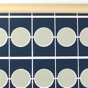 May include: Wallpaper roll with a repeating pattern of light grey circles within navy blue squares, connected by white lines. The roll is beige and is at the top. The design is modern and geometric, suitable for interior decoration.