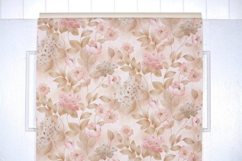 Puede incluir: Papel pintado floral con un patr&oacute;n repetido de flores rosas y beige, hojas verdes y beige y tallos beige. El papel pintado se muestra en un marco blanco, mostrando los detalles y la paleta de colores.
