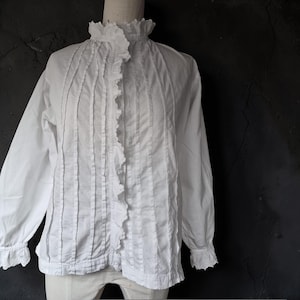 Vintage white cotton blouse from the 1920s with scalloped trim, decorative pintucks, and ruffles