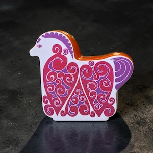 Può includere: Una statuetta animale stilizzata con base bianca e complessi motivi a spirale color magenta e viola. La figura presenta una finitura liscia e lucida con un bordo superiore arancione brillante, mostrando una silhouette distinta e curva.