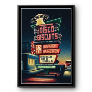 May include: A framed poster with a retro design featuring the text "The Disco Biscuits" in neon lights. The poster advertises a concert at Heuser Park, King of Prussia, PA, with dates July 25 and 26, and the names of the performers.