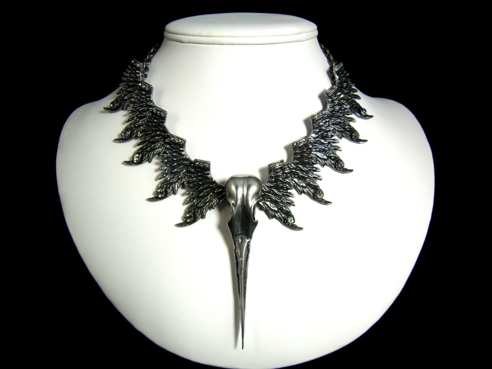 Egret skull and wing gothic necklace in pewter with gray crystals, displayed on white bust.