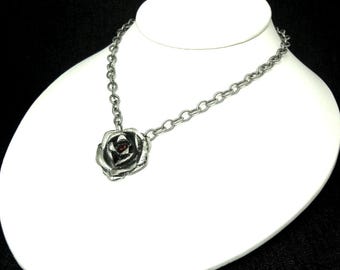 May include: A silver chain necklace with a silver rose pendant featuring a red gemstone in the center.