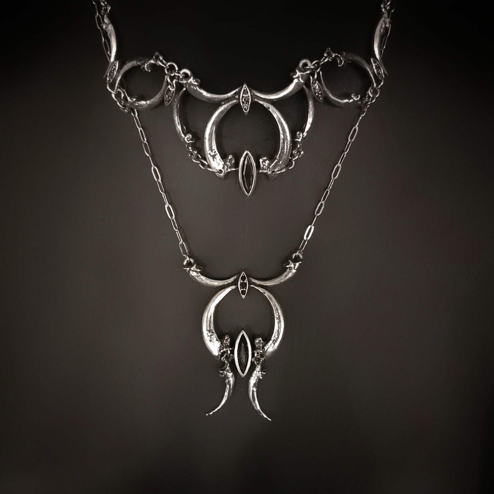 NYX choker layered with pendant necklace, featuring bird claws and dark crystal accents in gothic style.