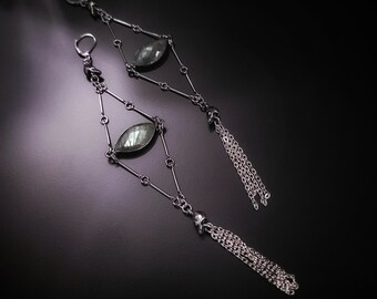 May include: A pair of silver earrings with a dark green gemstone and a chain tassel.