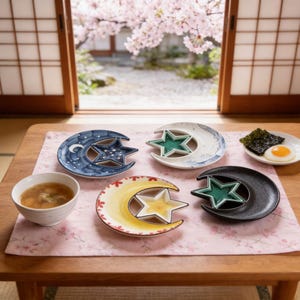 May include: A selection of ceramic plates in crescent moon and star designs. The plates are in shades of blue, white, yellow, and black, with green star-shaped inserts. A bowl of soup and a small plate of food are also visible.