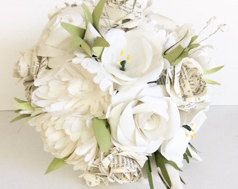 May include: A handcrafted bouquet of paper flowers in shades of white and cream. Some flowers are made from book pages, adding a vintage touch. Green paper leaves and delicate silver accents complete the arrangement.
