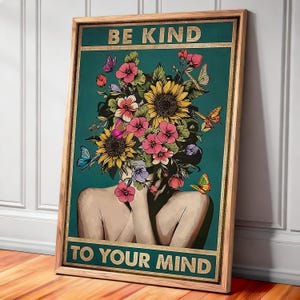May include: A framed art print with the words "BE KIND TO YOUR MIND" in gold lettering. The artwork features a woman with a floral headpiece of sunflowers and pink flowers, with butterflies. The background is teal.