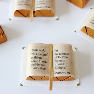May include: A small, gold-colored book with a white background. The book has a ribbon bookmark and the text "Jesus said, "Let the little children come to me, and do not hinder them for the kingdom of Heaven belongs to such as these." Matthew 19:14"