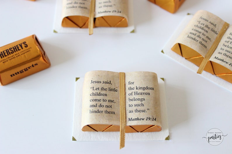 May include: A small, gold-colored book with a white background. The book has a ribbon bookmark and the text "Jesus said, "Let the little children come to me, and do not hinder them for the kingdom of Heaven belongs to such as these." Matthew 19:14"