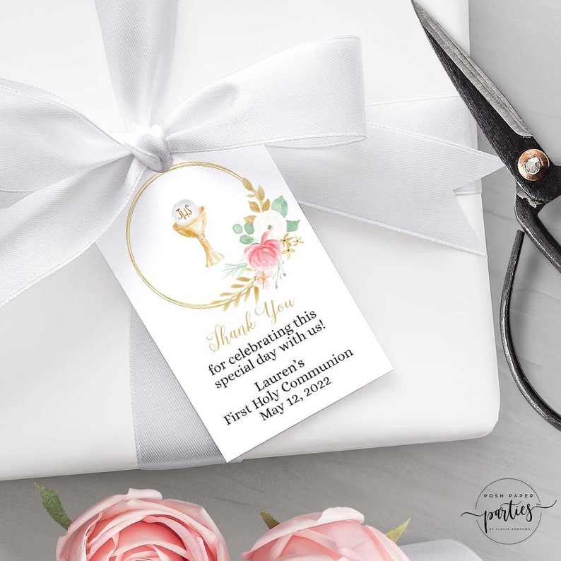 May include: A white thank you tag with gold and pink floral accents. The tag features a gold circle with a chalice and host inside. The text reads "Thank You for celebrating this special day with us! Lauren's First Holy Communion May 12, 2022".