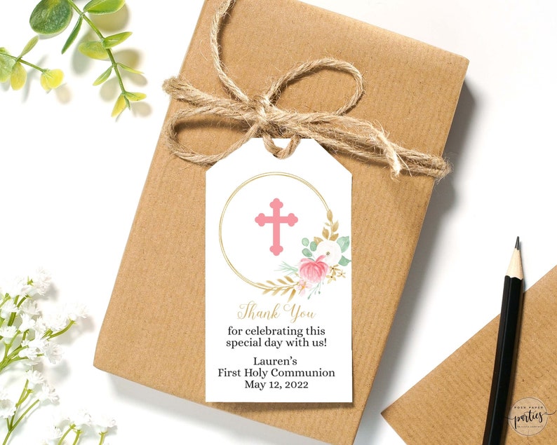 Pode incluir: Uma etiqueta de agradecimento branca com um c&iacute;rculo dourado e uma cruz rosa. A etiqueta tem um design floral com flores cor-de-rosa e folhas douradas. O texto na etiqueta diz "Obrigado por celebrar este dia especial connosco! A Primeira Comunh&atilde;o da Lauren a 12 de maio de 2022".
