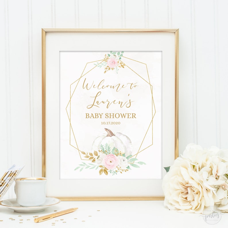 May include: A gold geometric frame with a white pumpkin, pink and white flowers, and greenery. The text "Welcome to Lauren's Baby Shower 10.17.2020" is inside the frame.