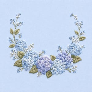 May include: A detailed embroidery of a half-circle floral wreath. The wreath features blue and purple hydrangea blooms, small white flowers, and green leaves on a light blue background. The embroidery is finely stitched.