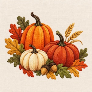Può includere: Un ricamo su tessuto chiaro raffigurante due grandi zucche arancioni, una zucca bianca più piccola, due ghiande marroni e diverse foglie autunnali nei toni del verde, giallo e rosso, arricchito da due spighe di grano dorate.