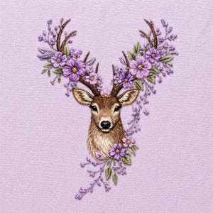 May include: Embroidered image of a deer head with brown fur and antlers adorned with purple flowers and green leaves. The background is a light purple fabric, creating a soft, textured appearance. The floral design adds a touch of nature.