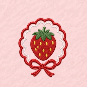 May include: Embroidered strawberry design with a red bow. The strawberry is red with yellow seeds and green leaves. The design is framed by a scalloped border in red and white, set against a pink background.