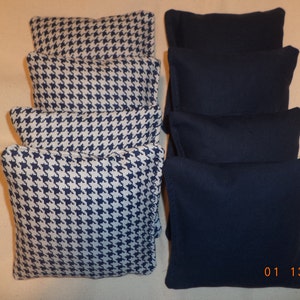 May include: A collection of eight bean bags. Four bean bags feature a navy blue and white houndstooth pattern. The other four bean bags are a solid navy blue color. The bean bags are rectangular and appear to be made of fabric.