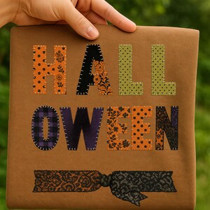 Pode incluir: Uma placa castanha com tema de Halloween com a palavra "HALLOWEEN" escrita em letras coloridas e estampadas. As letras são costuradas na placa e há um laço de renda decorativo na parte inferior. O fundo está desfocado.