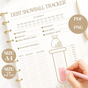 Pode incluir: Um rastreador de bola de neve de dívida com encadernação em espiral dourada. As páginas bege apresentam instruções para rastrear a dívida, com o texto "DEBT SNOWBALL TRACKER." Inclui tamanhos: A4 e US 8,5" x 11" (aprox. 21,6 x 27,9 cm). Uma mão usa uma caneta rosa.