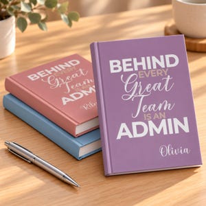 以下が含まれることがあります： 紫、ダスティローズ、水色のハードカバーノート3冊。それぞれに「BEHIND EVERY Great Team IS AN ADMIN」という白い文字と下部にパーソナライズされた名前が印刷されており、銀色の金属製ボールペンが添えられています。