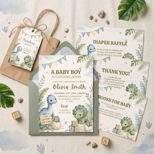May include: A set of baby shower stationery featuring dinosaur illustrations, including a main invitation with the text A BABY BOY IS HATCHING SOON, a diaper raffle card, a thank you note, a books for baby card, and a gift tag on a brown bag.