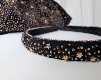 May include: Black velvet headband and matching accessory, embellished with iridescent beads and gold star accents. The headband is approximately 1 inch wide. The accessory is in the background. The items are on a white surface.