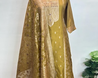 May include: Olive green salwar kameez ensemble with a matching dupatta. The outfit features intricate gold brocade detailing on the neckline, sleeves, and dupatta border. The fabric has a subtle sheen, and the design includes a paisley motif.