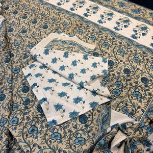 May include: A floral patterned bedding set in shades of blue and beige. The set includes a flat sheet, fitted sheet, and pillowcases. The design features blue flowers and vines on a beige background, with a contrasting white border.