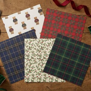Pu&ograve; includere: Un assortimento di carta da regalo fantasia, con orsetti, motivi scozzesi e decorazioni di agrifoglio, disposti su una superficie di legno. Sono presenti forbici, nastri ed etichette regalo.
