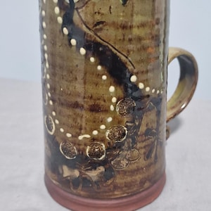 May include: A set of three ceramic mugs with a speckled, matte finish. The mugs are in cream, light grey, and dark grey. Each mug has a simple, minimalist design, suitable for coffee or tea.