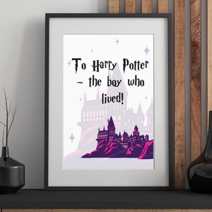 以下が含まれることがあります： 黒い文字で「To Harry Potter - the boy who lived!」と書かれた額入りのアートプリント。プリントには、紫とピンクの城のイラストが描かれています。アートワークは黒いフレームに入っています。
